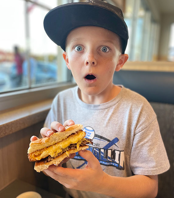 A boy gasps in amazement at the cheese in his CurderBurger.